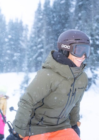People enjoying snowboarding in a snowy, forested mountain landscape during winter.
