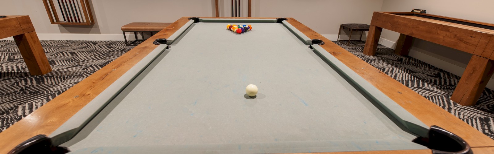 The image shows a pool table with balls arranged for a game, located in a room with wall art and mirrors.