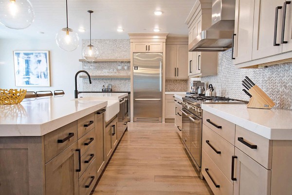 A modern kitchen with wooden cabinets, stainless steel appliances, white countertops, a center island, and pendant lights.