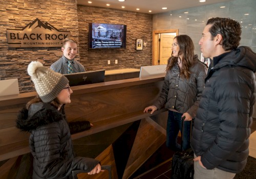 A family is checking into Black Rock Mountain Resort at the reception desk while the receptionist assists them with a smile, wearing winter gear.