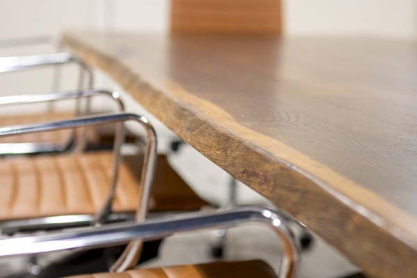 A wooden table with chrome and leather chairs in a modern, minimalistic office or meeting room setting.