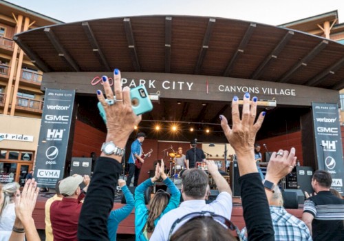 People enjoying a live concert at Park City's Canyons Village, hands raised and phones out to capture the moment.