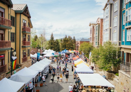 a photo of downtown park city on the day of the park sill sunday market. tents are put up of people selling goods with families walking around the area at different booths