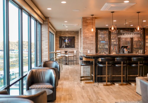 A modern lounge with large windows, leather seating, a bar counter, and hanging lights, featuring a warm and inviting atmosphere.
