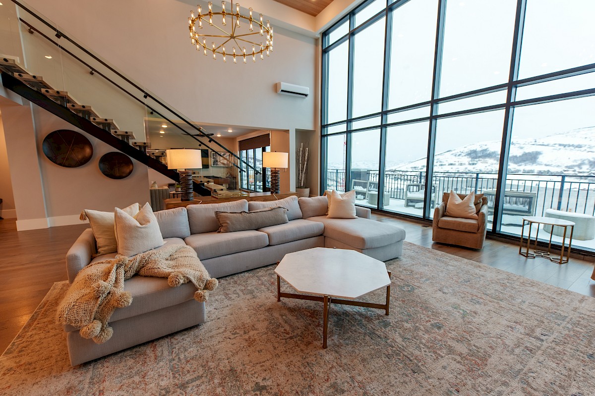 A spacious living area with a large sectional sofa, modern decor, and a view of snowy mountains through floor-to-ceiling windows.