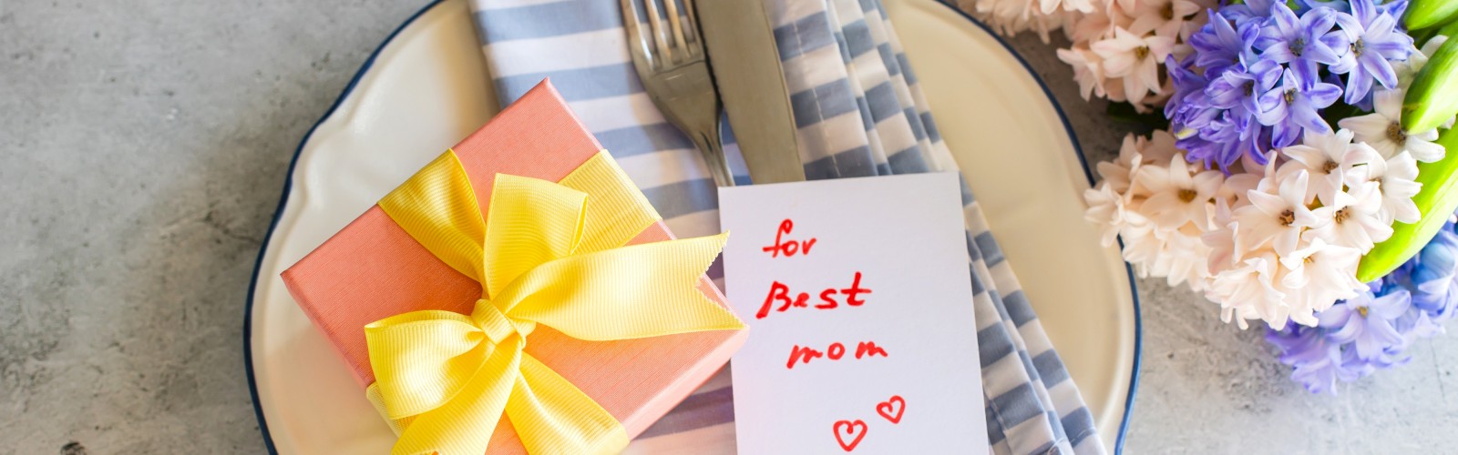 A beautifully arranged table setting with a wrapped gift, a note saying 