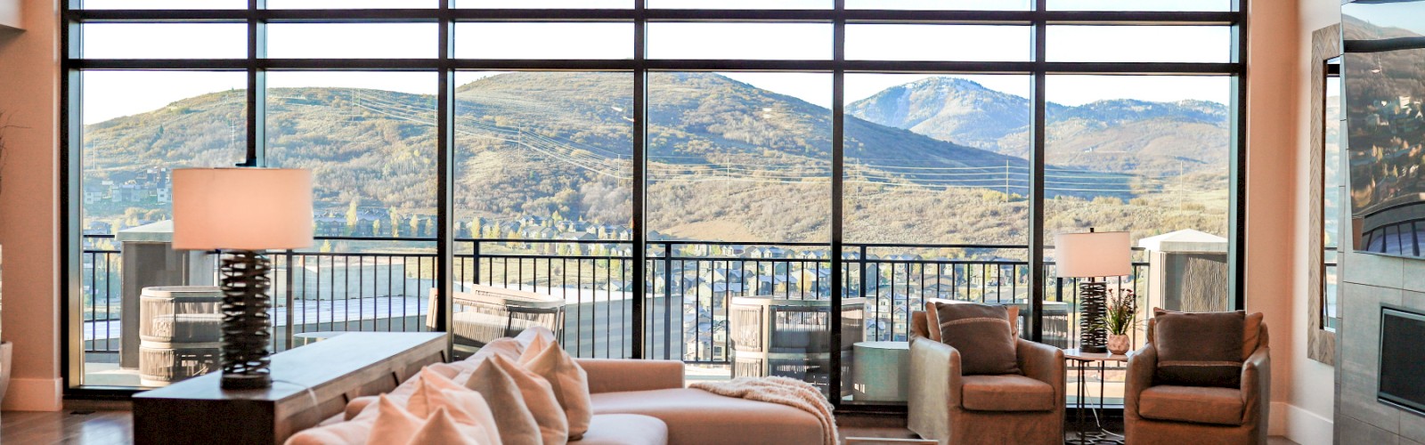 A modern living room with large windows revealing mountain views and a cozy, stylish interior decor.