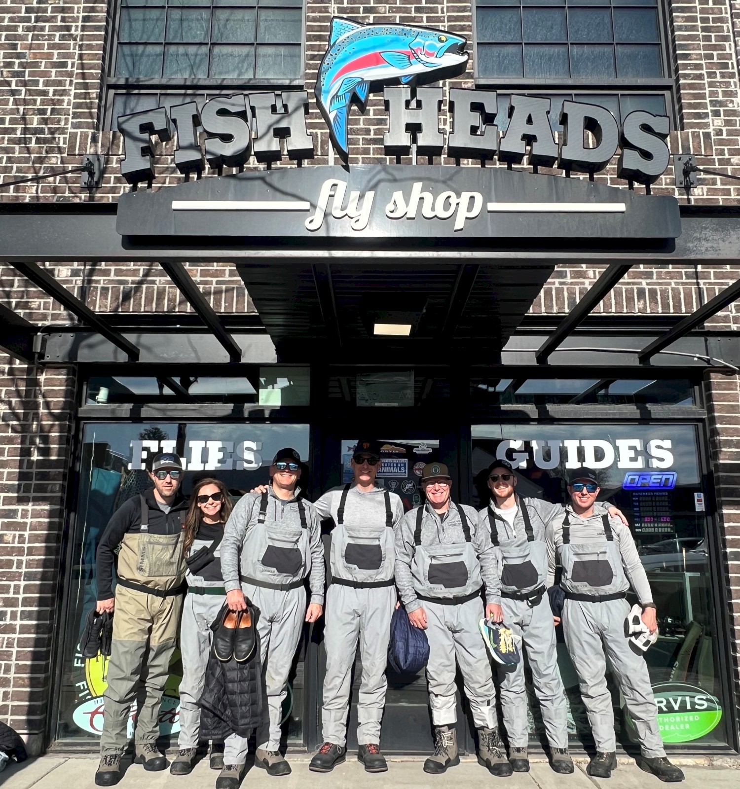 A group of people in fishing gear stand outside 
