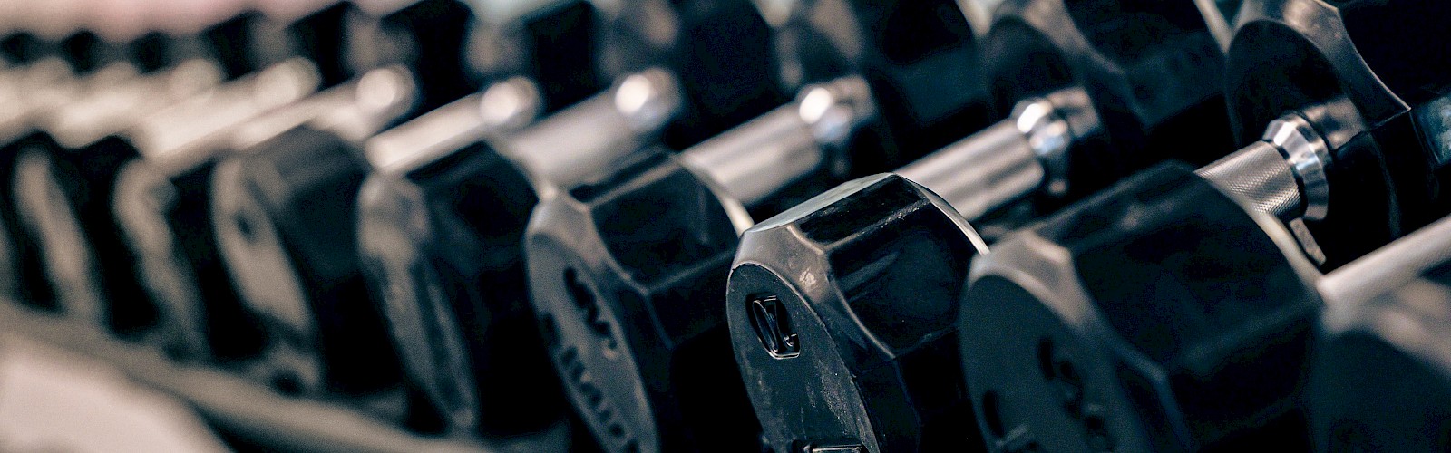 Stacked black dumbbells on a rack for weight training exercises.