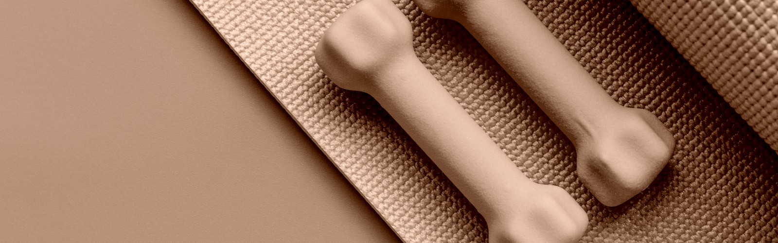 Two small dumbbells rest on a textured exercise mat, both in a beige color scheme, creating a cohesive workout setup.