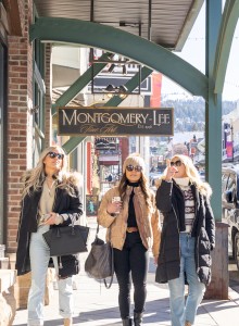 Three people walk on a sidewalk under a 