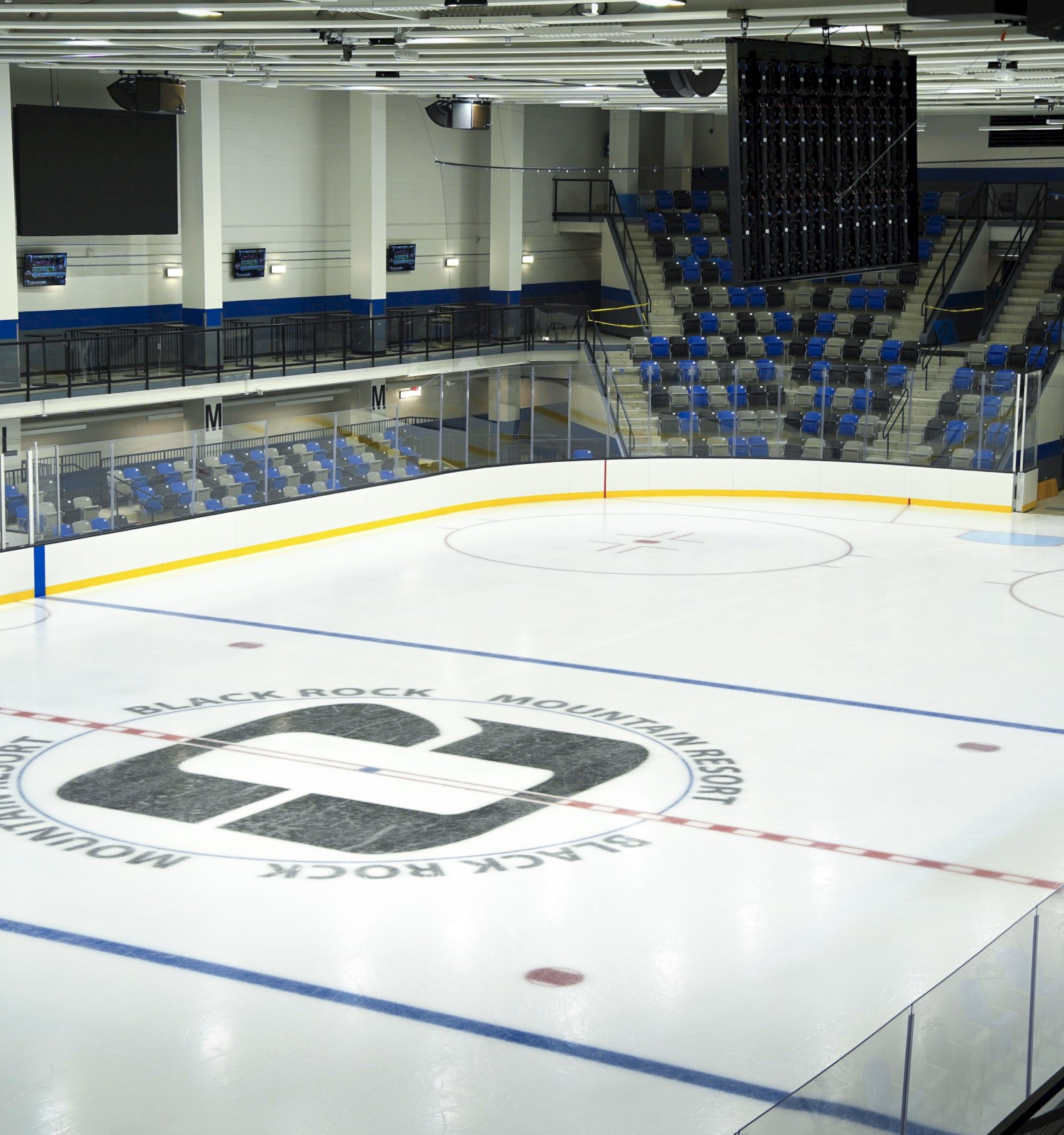 An empty ice hockey rink with seating and a scoreboard in the arena, marked with 