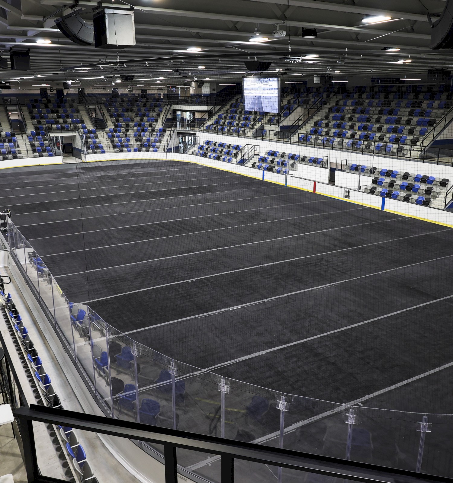 An empty indoor hockey rink with seating and a glass barrier surrounds the ice surface inside an arena.