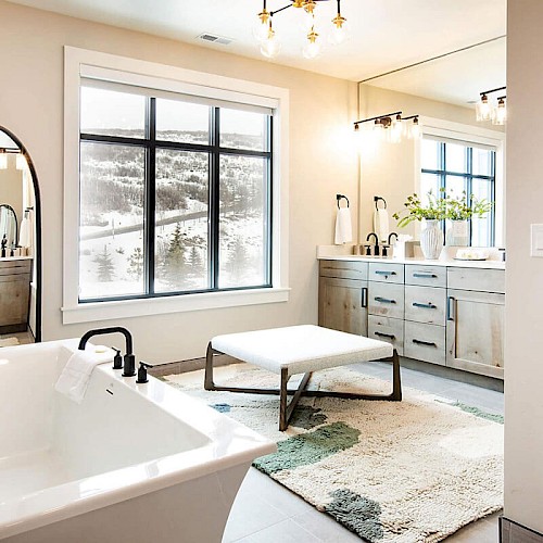 A modern, bright bathroom with a freestanding tub, large window, double vanity, full-length mirror, and neutral tones, stylish and airy.