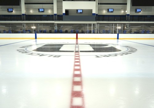 An ice hockey rink with red center line, blue lines, and team logos on the ice.