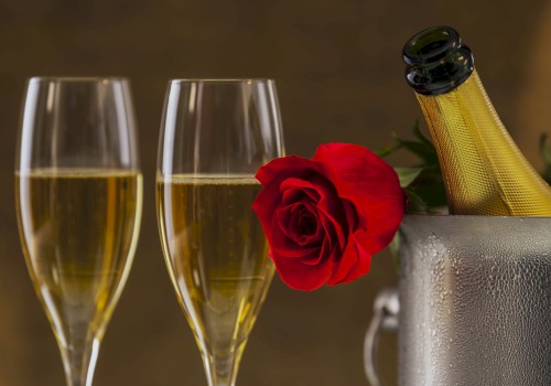 Two champagne flutes, a red rose, and a champagne bottle in a cooler, suggesting a celebratory moment.